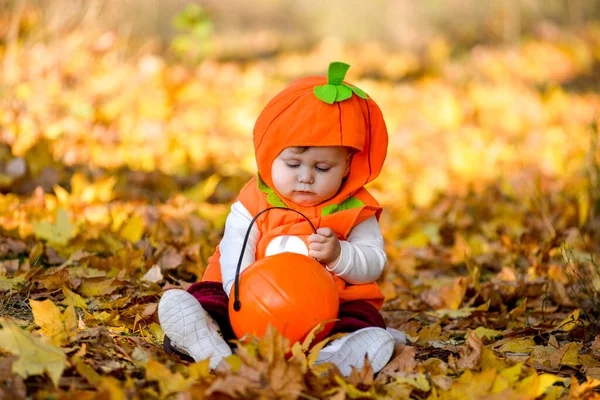Child in pumpkin suit on background of autumn leaves Royalty Free Stock Images