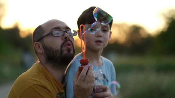 Vater und Sohn pusten Blasen, haben Spaß mit der Familie, das Kind hat Spaß mit seinem Vater. Die Einheit von Sohn und Vater — Stockvideo