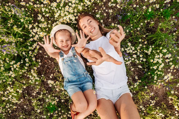 白いTシャツを着た母親と娘がカモミール畑に横たわっています — ストック写真