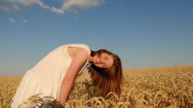 Genç kız sarı bir tarlada yavaşça yürür, buğday başaklarına elleriyle dokunur. Güzel kaygısız kadın buğday tarlasında doğanın ve güneşin tadını çıkarıyor.
