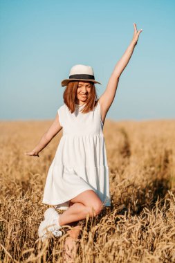 Genç kız sarı bir tarlada yavaşça yürür, buğday başaklarına elleriyle dokunur. Güzel kaygısız kadın buğday tarlasında doğanın ve güneşin tadını çıkarıyor.