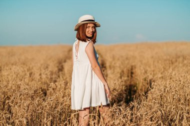 Genç kız sarı bir tarlada yavaşça yürür, buğday başaklarına elleriyle dokunur. Güzel kaygısız kadın buğday tarlasında doğanın ve güneşin tadını çıkarıyor.