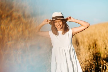 Genç kız sarı bir tarlada yavaşça yürür, buğday başaklarına elleriyle dokunur. Güzel kaygısız kadın buğday tarlasında doğanın ve güneşin tadını çıkarıyor.