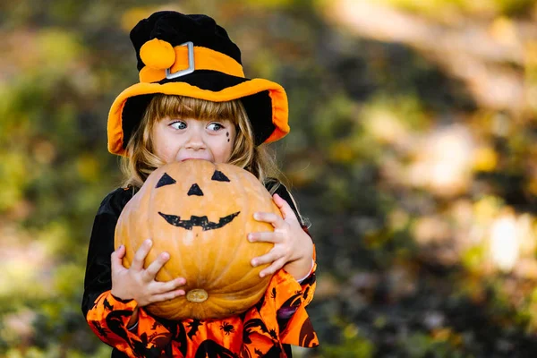 Joyeux Halloween. Petite sorcière mignonne avec une citrouille dans les mains. — Photo
