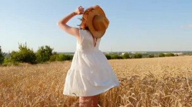 Genç kız sarı bir tarlada yavaşça yürür, buğday başaklarına elleriyle dokunur. Güzel kaygısız kadın buğday tarlasında doğanın ve güneşin tadını çıkarıyor.