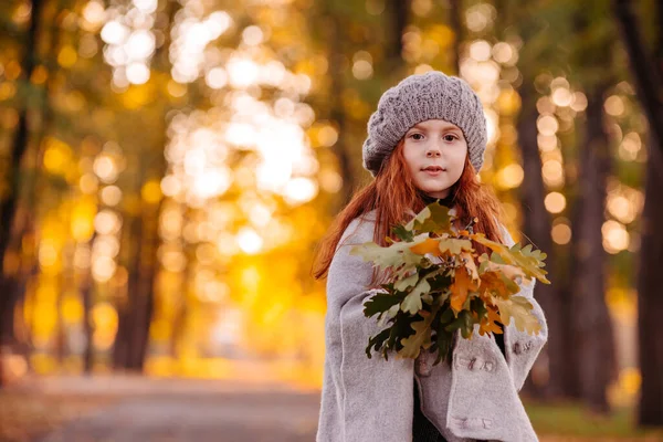 Hermosa chica cabeza roja sosteniendo hojas de otoño y posando para la cámara, foto colorida — Foto de Stock