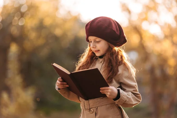 Menina ruiva bonito lendo um livro no parque no outono. Conceito de aprendizagem. Estilo retrô. Moda de crianças. — Fotografia de Stock