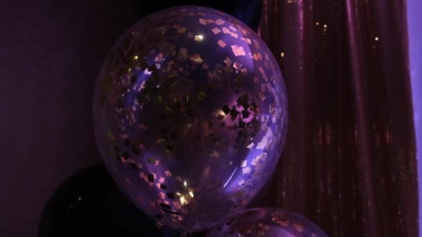 Сферы и прозрачные воздушные шары с золотыми конфетти на теплом приглушенном фоне крупным планом. Гелиевые шарики. Атмосфера. — стоковое видео