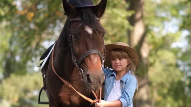 Schattig klein meisje met lang haar streelt een mooi paard buiten — Stockvideo