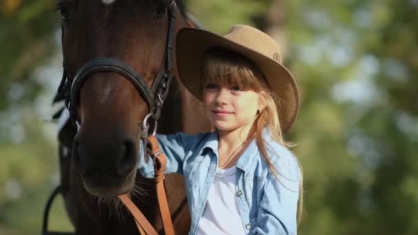 Cute little girl with long hair stroking a beautiful horse outdoors — Stock Video