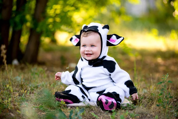 Year of the bull. A child in a fancy dress of a bull on a meadow smiles cute. Kid in Halloween Cow Costume