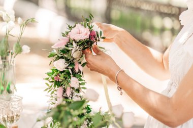 Atölye çiçekçisi, buketler ve çiçek düzenlemeleri yapıyor. Kız kafasında çelenk yapıyor. Bitki ve çiçeklerle çelenk dokuma işlemi. Çiçekçilerin yakın çekim dersi. Boşluğu kopyala