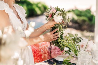 Atölye çiçekçisi, buketler ve çiçek düzenlemeleri yapıyor. Kız kafasında çelenk yapıyor. Bitki ve çiçeklerle çelenk dokuma işlemi. Çiçekçilerin yakın çekim dersi. Boşluğu kopyala
