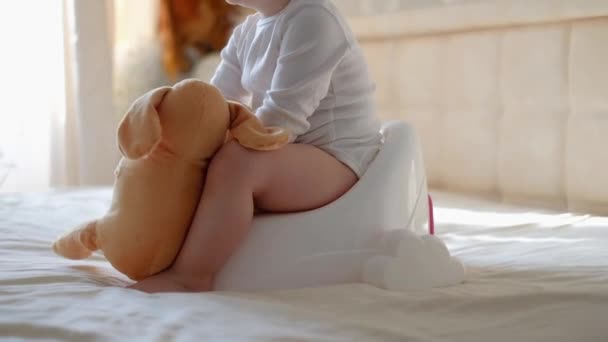 Des jambes de bébé suspendues à un pot. Le garçon est assis sur le pot. Bébé drôle assis sur le pot du matin dans la chambre — Video