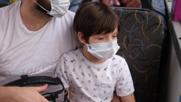 Um pai e uma criança viajam em transportes públicos usando máscaras protetoras. Protecção contra o coronavírus — Vídeo de Stock