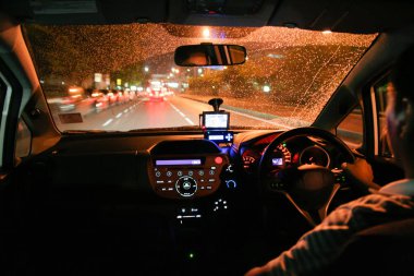 Bir şehirde yağmur aracılığıyla gece sürüş. Winshield üzerinde yağmur damlaları