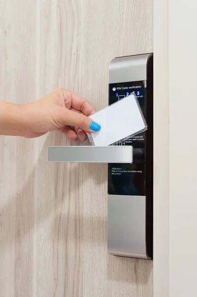 Closeup of woman hand tap key card on electronic door lock to unlock the door