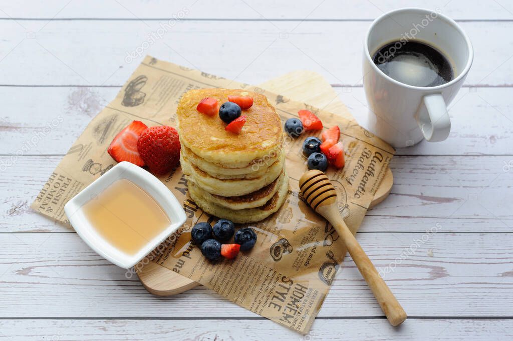 A cup of coffee and pancakes with ingredients on a white wooden background. Prepared ingredients for baking