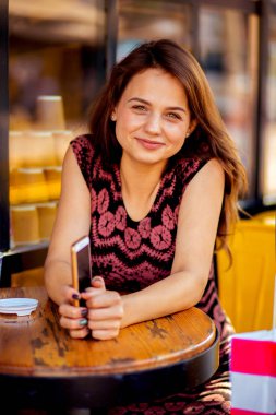 Bir telefonla sokakta bir kafede bir masada güzel kadın