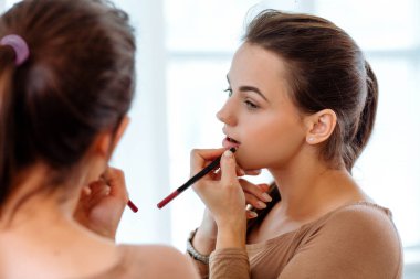 Kadın bir ayna önünde kırmızı ruj dudakları boyalar