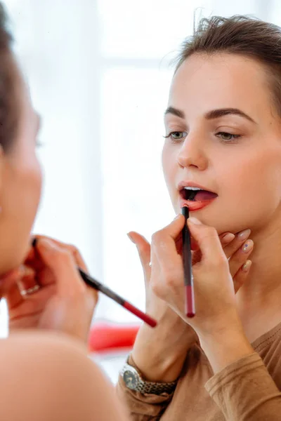 女性の鏡の前で赤い口紅唇を塗料します — ストック写真
