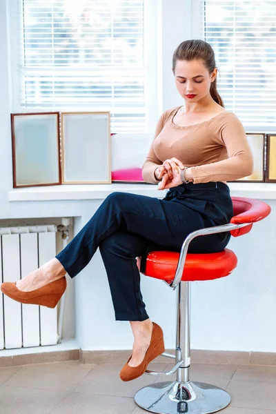 Successful modern business woman on the chair looks at the time