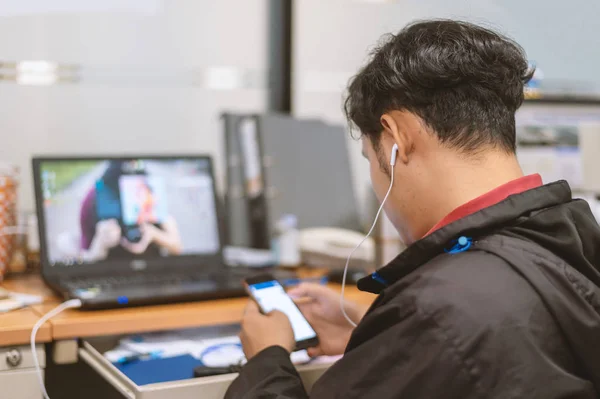 business man working and play smart phone in office with soft-focus and over light in the background