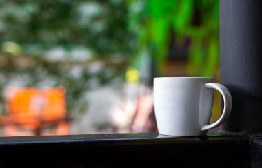 Yumuşak odaklı ve arka planında ışık olan beyaz kahve bardağını kapat.