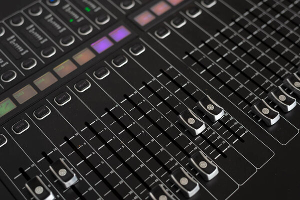 Closeup of sound mixer in recording studio with soft-focus and over light in the background