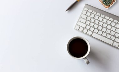 Üst kat ofis masası. Beyaz arkaplanda kahve fincanı, kalem, klavye ve diğer ofis ekipmanları