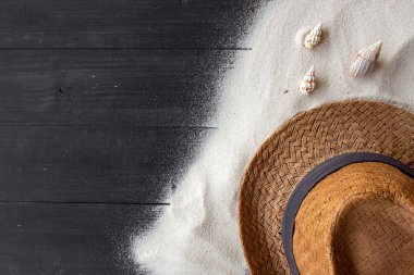 Yaz arkaplanı. Siyah ahşap arka planda şapka ve kum. en üstteki görünüm