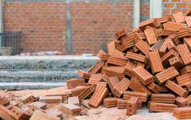 İnşaat alanındaki kırmızı tuğlalardan oluşan grubu kapatırken, arka planda hafif odaklı ve ışığın üzerinde
