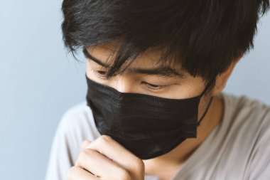 Koronavirüsü (COVIT-19) korumak için maske takan yakın plan erkekler, arka planda hafif odak ve ışık altında