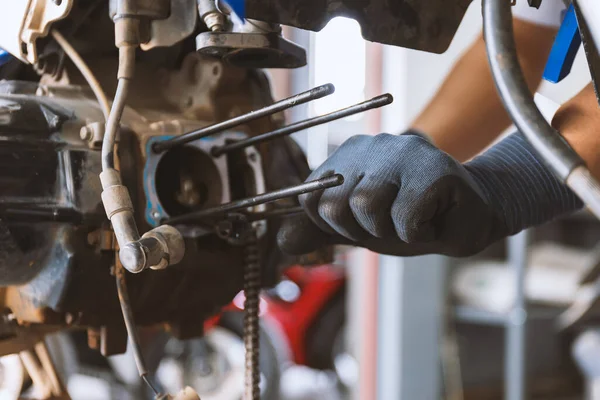 Motor tarzı. Motosikleti tamir eden tamirci arka planda hafif odaklı ve ışığın üstünde