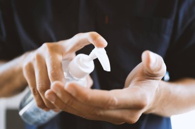 Yakın plan adam ellerini alkol jeliyle yıkıyor.% 75 'i virüs ve veba enfeksiyonunu önlüyor. Yumuşak odaklı ve arka planda ışık var.