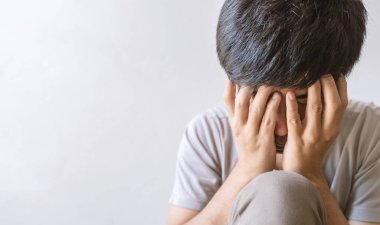Yalnız başına oturan yakın plan bir pişmanlık ya da korku hisseden ve elini yüzünü odaya daldıran adam. yumuşak odaklı ve arka plandaki ışığın üzerinde