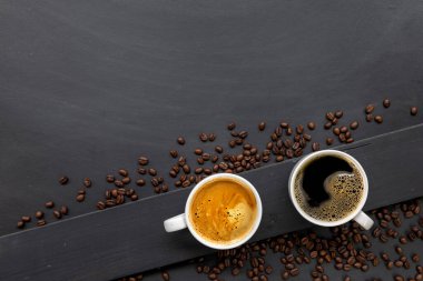 Siyah ahşap masa arkasında bir fincan kahve ve fasulye. en üstteki görünüm