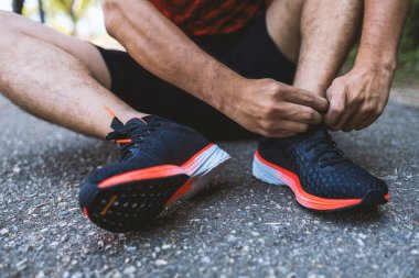 Yakın plan sporcusu hafif odaklı koşu ayakkabıları bağlıyor ve arka planda ışık var. fitness, egzersiz, egzersiz ve sağlıklı yaşam tarzı konsepti.