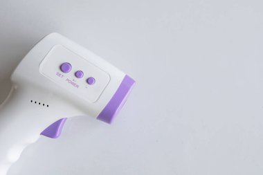 Beyaz masa arka planında yakın plan kızılötesi termometre. Üst Manzara. metin için ayrıntı