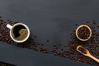 Siyah ahşap masa arkasında bir fincan kahve ve fasulye. en üstteki görünüm