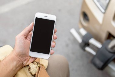 Yakın plan, arka planda hafif odaklı ve ışık altında akıllı telefonu tutuyor.