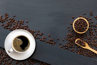 Siyah ahşap masa arkasında bir fincan kahve ve fasulye. en üstteki görünüm