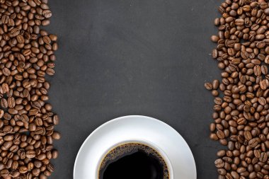 Siyah ahşap masa arkasında bir fincan kahve ve fasulye. en üstteki görünüm