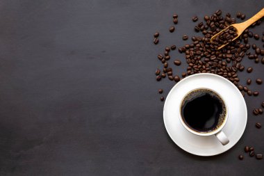 Siyah ahşap masa arkasında bir fincan kahve ve fasulye. en üstteki görünüm
