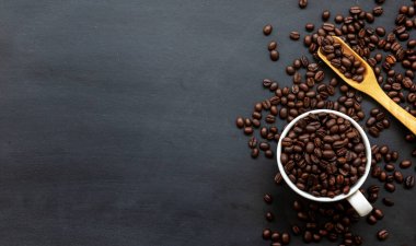 Siyah ahşap zemin üzerinde beyaz fincanda kahve çekirdeği. Üst Manzara. Metin için boşluk