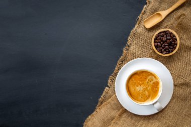 Siyah ahşap masa arkasında bir fincan kahve ve fasulye. en üstteki görünüm