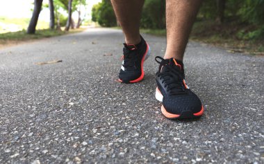 Parktaki yollarda koşan sporcu adam. Arka planda hafif odaklı ve ışığın üstünde.