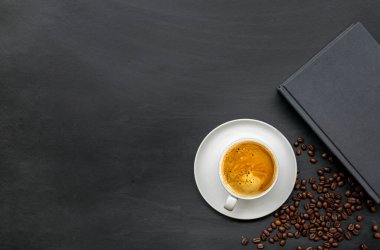 Siyah ahşap zemin üzerine bir fincan kahve ve kitap. Üst Manzara. Metin için boşluk