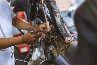 Motor tarzı. Motosikleti tamir eden tamirci arka planda hafif odaklı ve ışığın üstünde