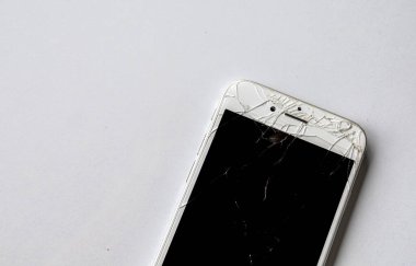 Beyaz masa arka planında kırık bir ekranı olan akıllı telefonu kapat